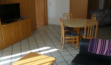 Großer Wohnraum mit Fernseher, Couch und Esstisch